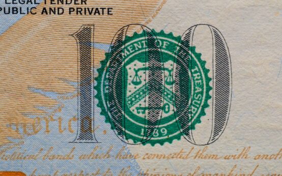Detailed view of the US 100 dollar bill showing the Treasury seal and printed text.