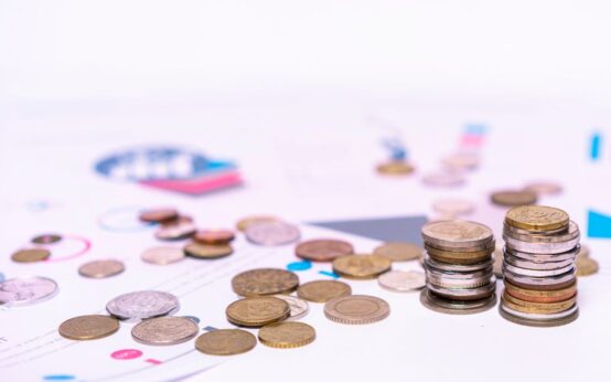 Stack of assorted coins with financial documents on a white background, highlighting the concept of savings.