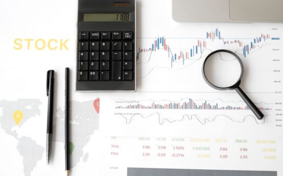 Flat lay of stock market analysis tools including calculator, graphs, and magnifying glass.